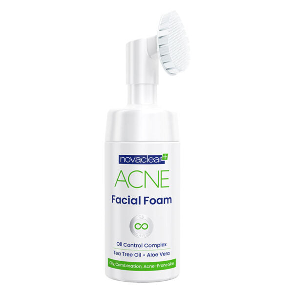 A bottle of Novaclear acne facial foam with a silicone brush applicator, primarily white in color with green and blue accents and text indicating its use for acne-prone skin.